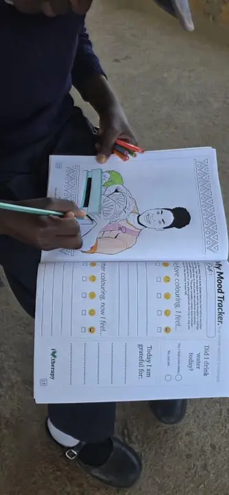 Close-up of a participant completing a mood and gratitude workbook.